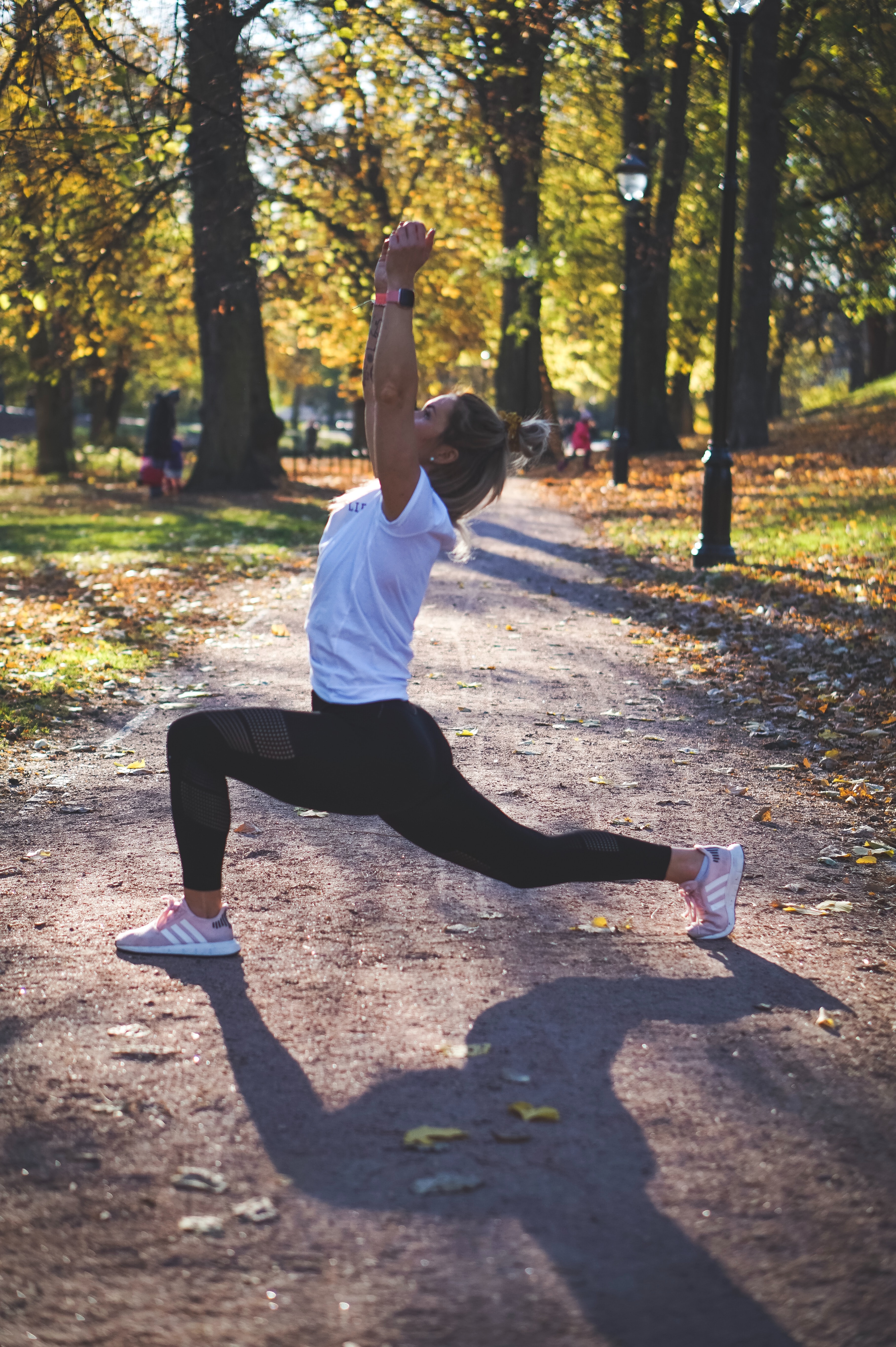 A young lady doing warrior I yoga pose outdoors.